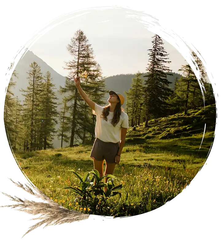 A woman in a field holds up a flower.